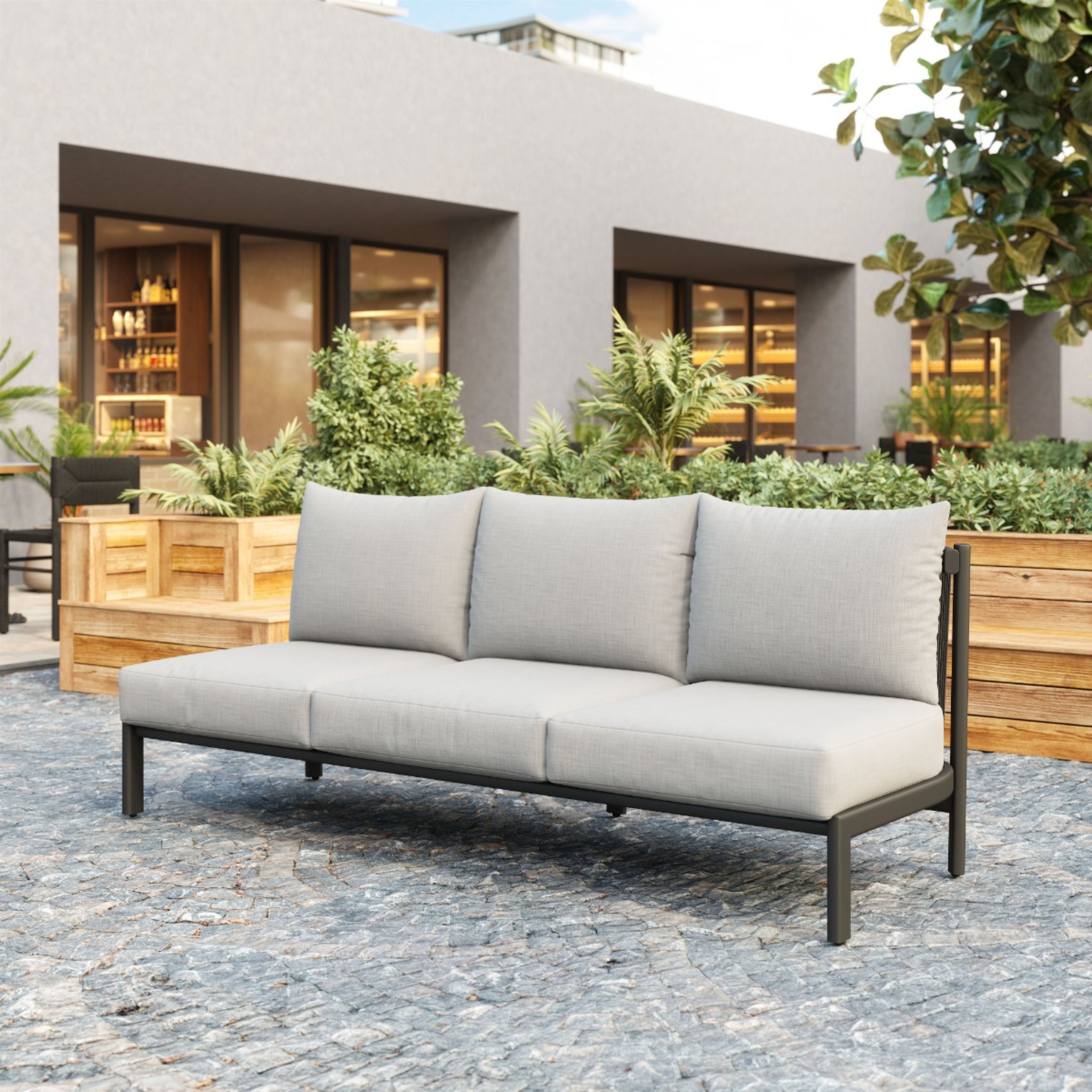 a-product-page-with-an-outdoor-sofa-with-gray-cushions-and-black-frame-placed-in-a-garden-setting-with-plants-and-a-paved-patio